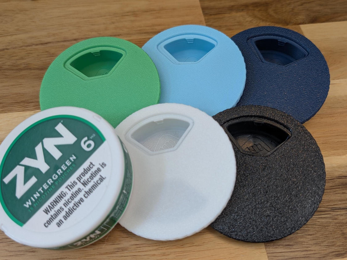 Five lid colors laid out with a nicotine pouch can for scale